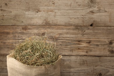 Burlap sack with dry herb on wooden table, top view. Space for text