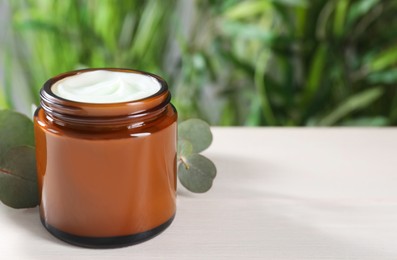 Photo of Jar of hand cream and eucalyptus branch on white table, space for text