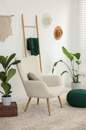 Comfortable armchair, pouf and houseplants in living room. Interior design