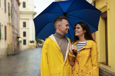 Photo of Lovely young couple with umbrella walking under rain on city street