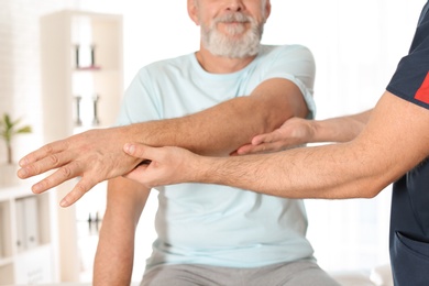 Photo of Physiotherapist working with patient in clinic, closeup. Rehabilitation therapy
