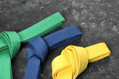 Photo of Colorful karate belts on gray background, closeup