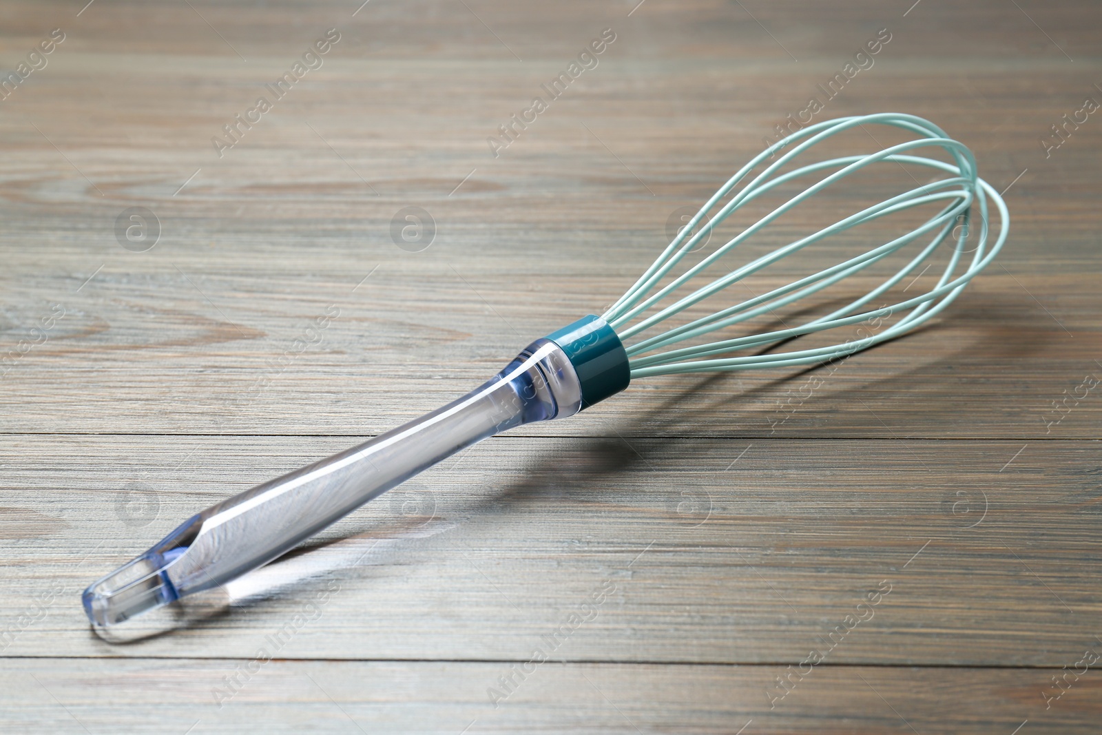 Photo of One whisk on wooden table, closeup. Kitchen tool