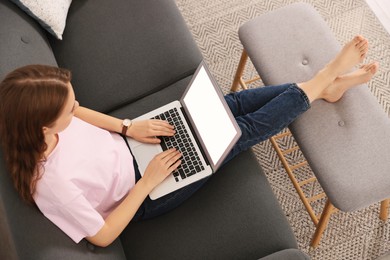 Woman with laptop on sofa at home, above view