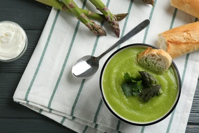 Photo of Delicious asparagus soup in bowl served on table, flat lay