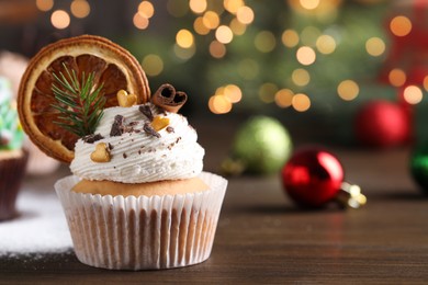 Photo of Beautifully decorated Christmas cupcake on wooden table, closeup. Space for text