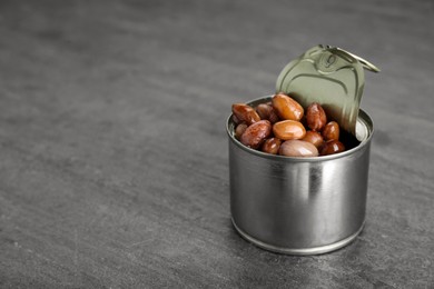 Tin can with kidney beans on gray table, space for text