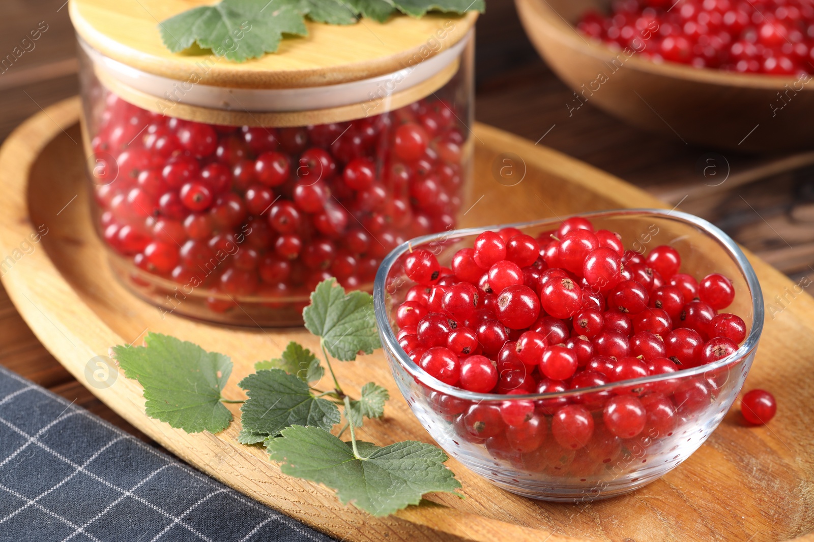 Photo of Ripe red currants and leaves on wooden table, closeup