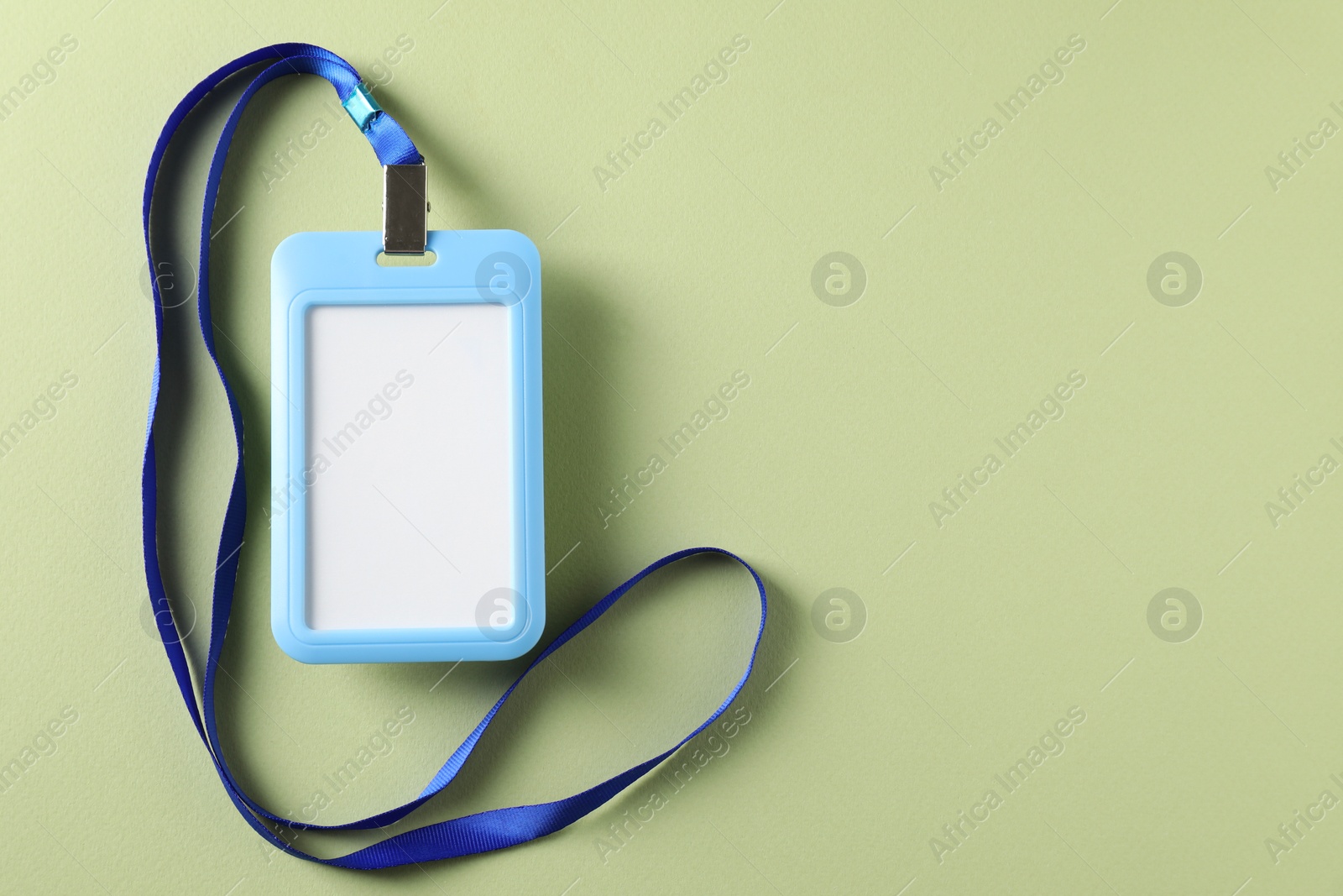 Photo of Blank light blue badge with string on green background, top view. Space for text