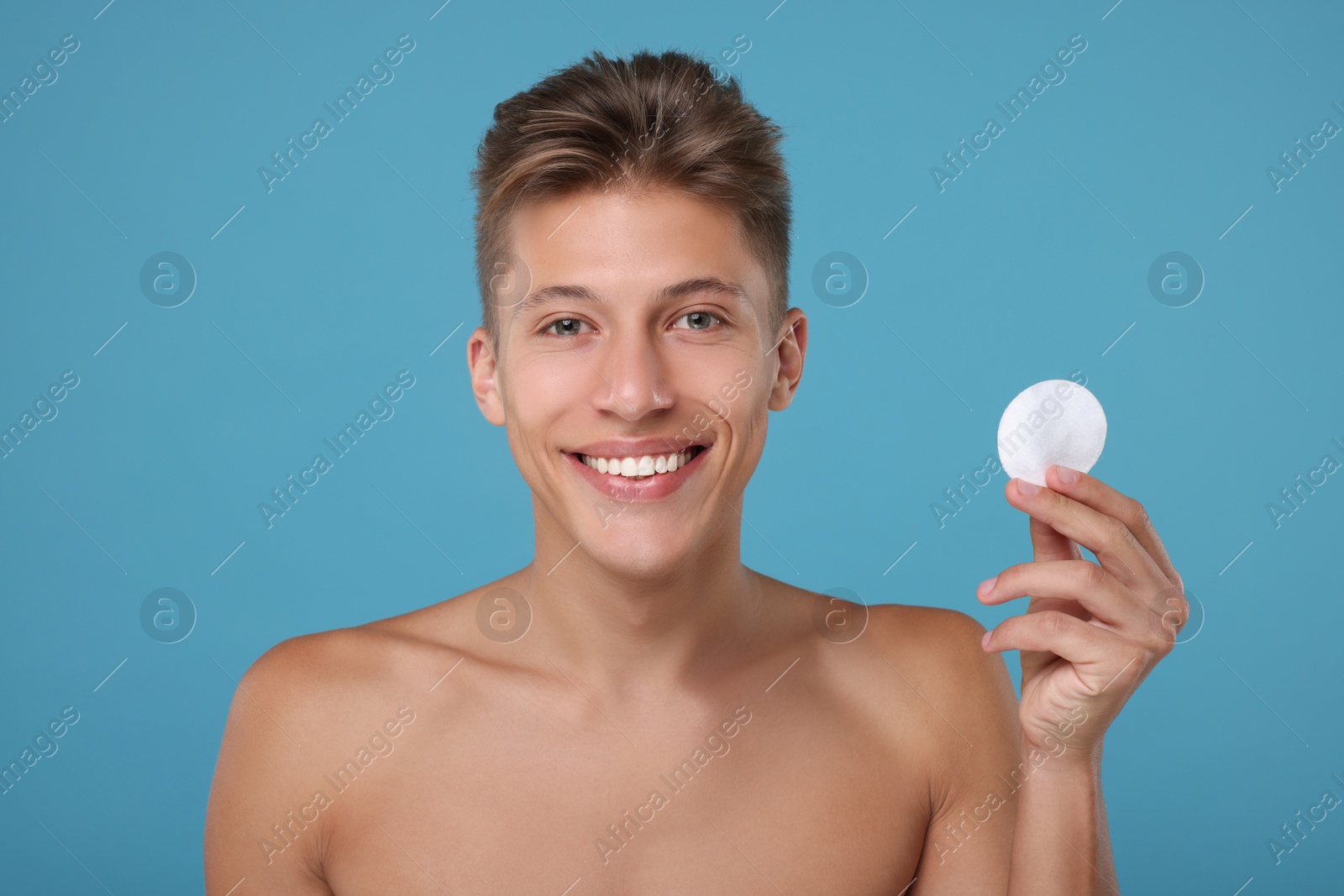 Photo of Handsome man with cotton pad on light blue background