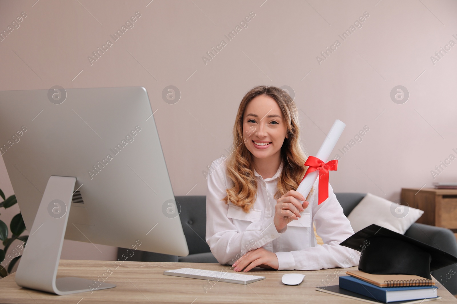 Photo of Happy student with graduation hat and diploma at workplace in office