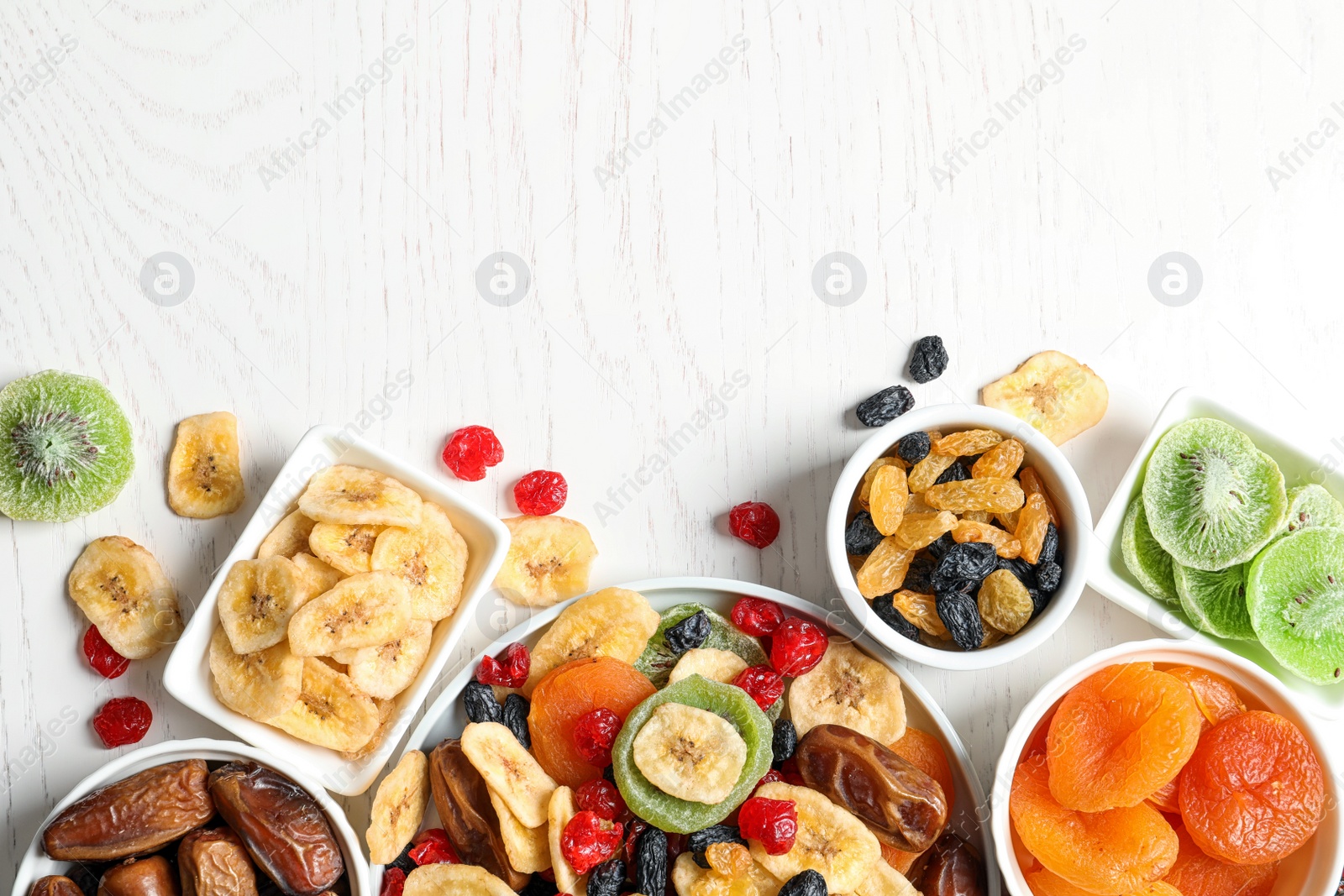 Photo of Bowls of different dried fruits on wooden background, top view with space for text. Healthy lifestyle