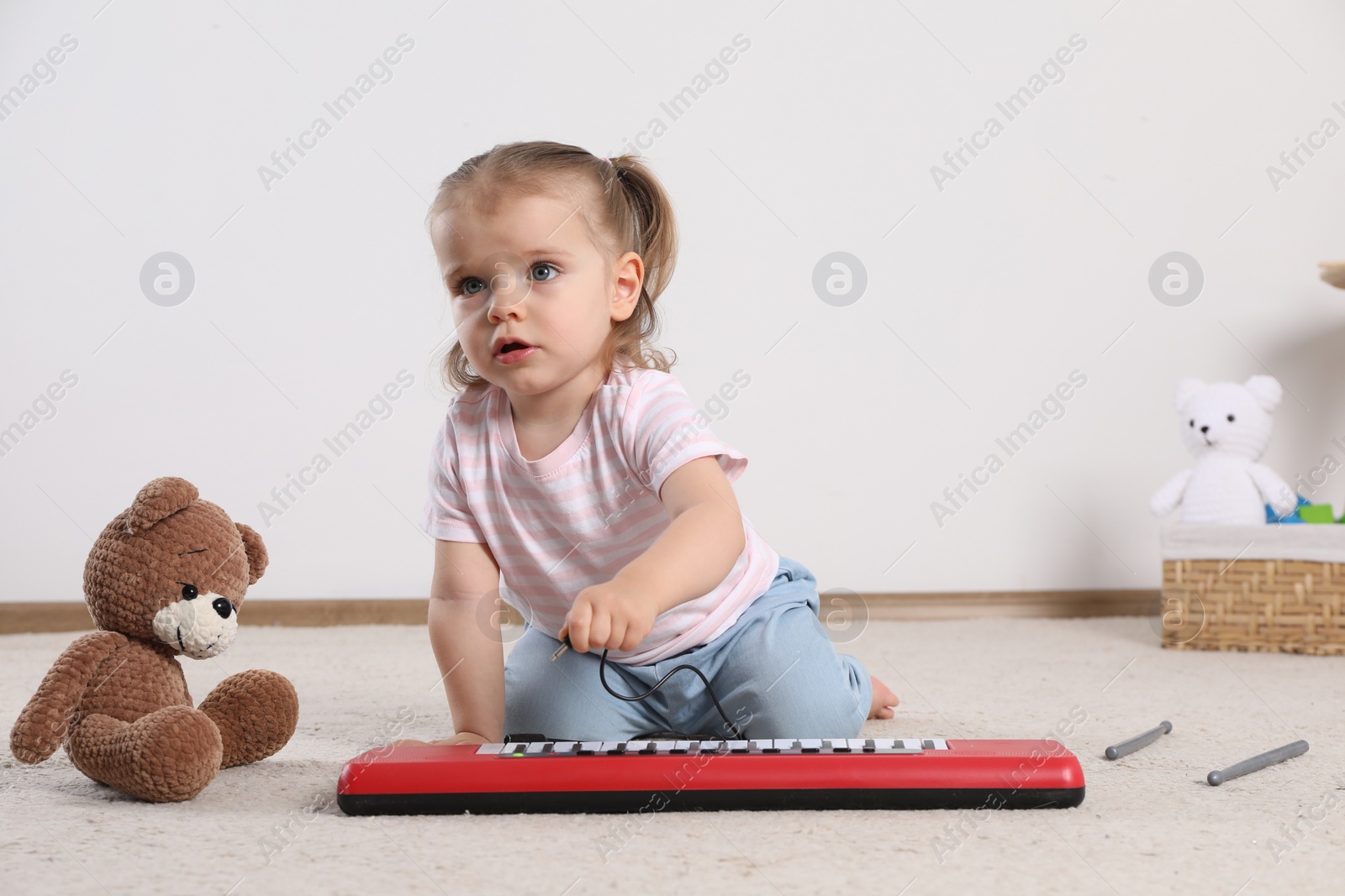 Photo of Cute little girl playing with toy piano at home