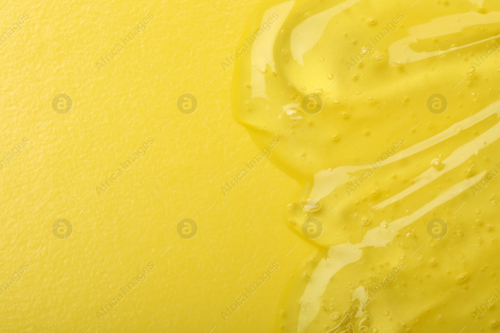 Photo of Pure transparent cosmetic gel on yellow background, top view