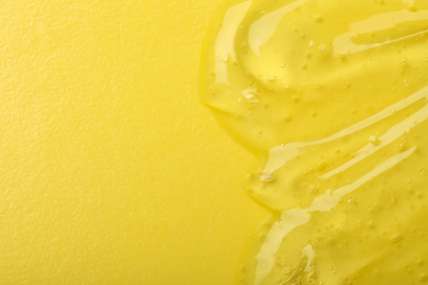 Photo of Pure transparent cosmetic gel on yellow background, top view