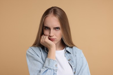 Portrait of resentful woman on beige background