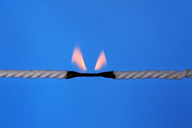 Burning rope at breaking point on color background