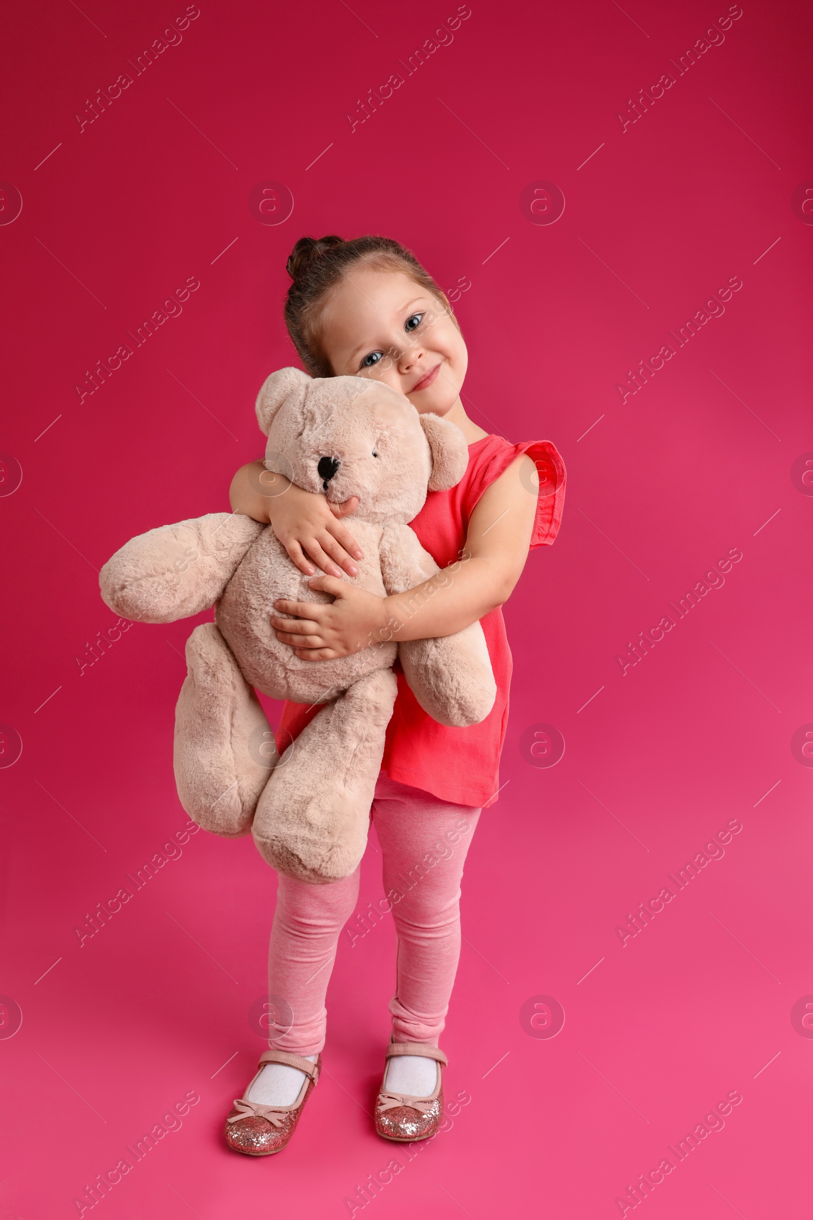 Photo of Cute little girl with teddy bear on pink background