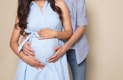 Pregnant woman and her husband on color background, closeup