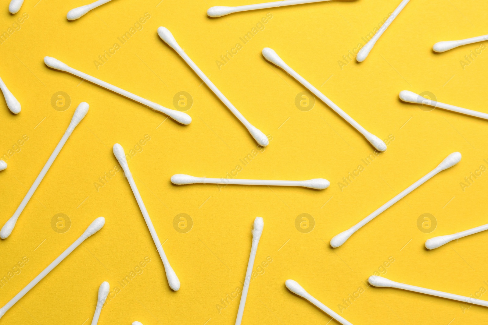 Photo of Many cotton buds on yellow background, flat lay