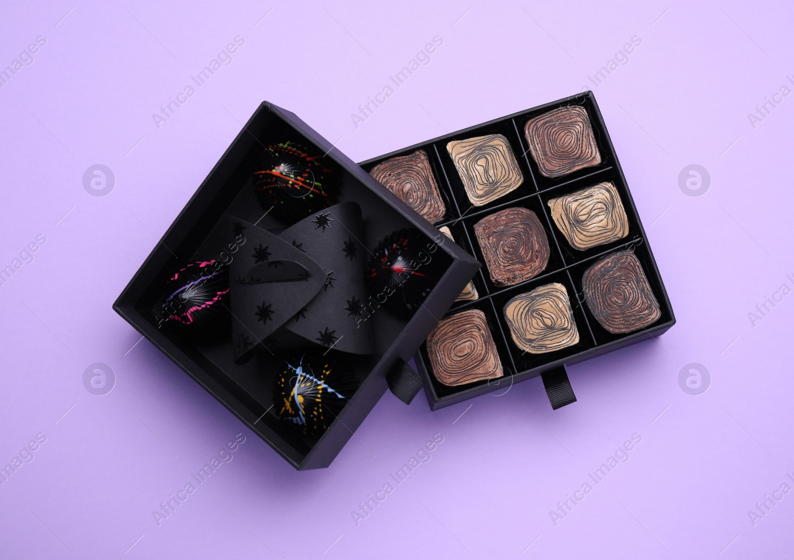 Photo of Boxes of tasty chocolate candies on violet background, flat lay
