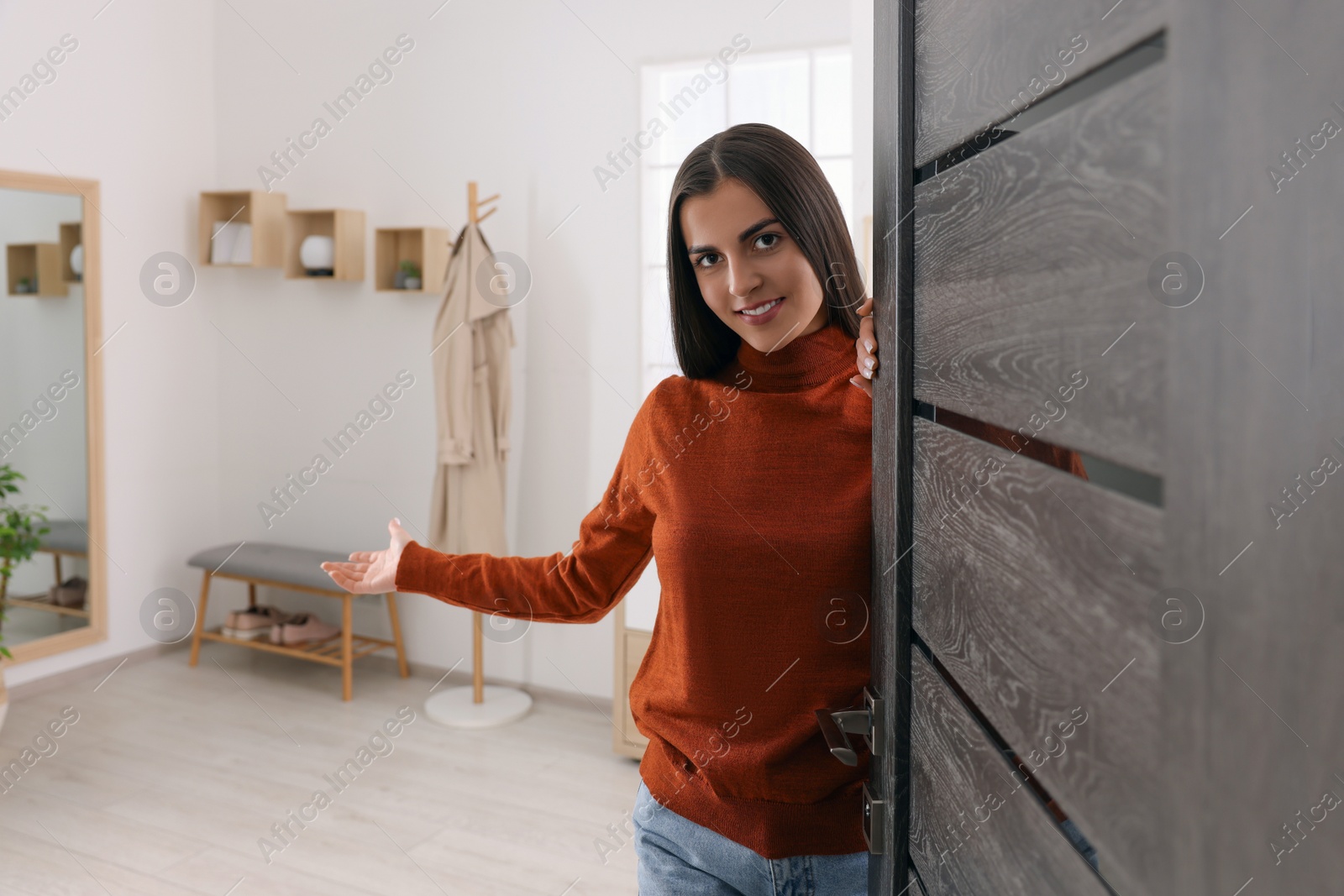 Photo of Happy woman welcoming near door, space for text. Invitation to come indoors