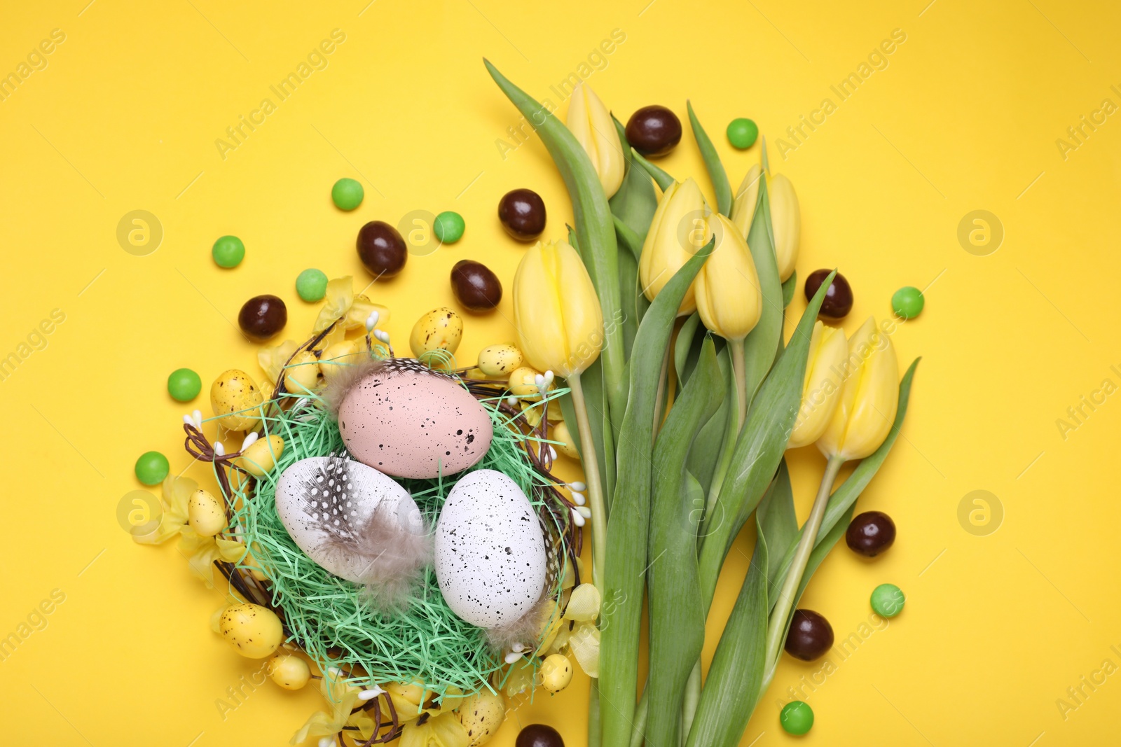 Photo of Flat lay composition with beautiful flowers and eggs on yellow background. Easter celebration