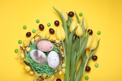 Flat lay composition with beautiful flowers and eggs on yellow background. Easter celebration