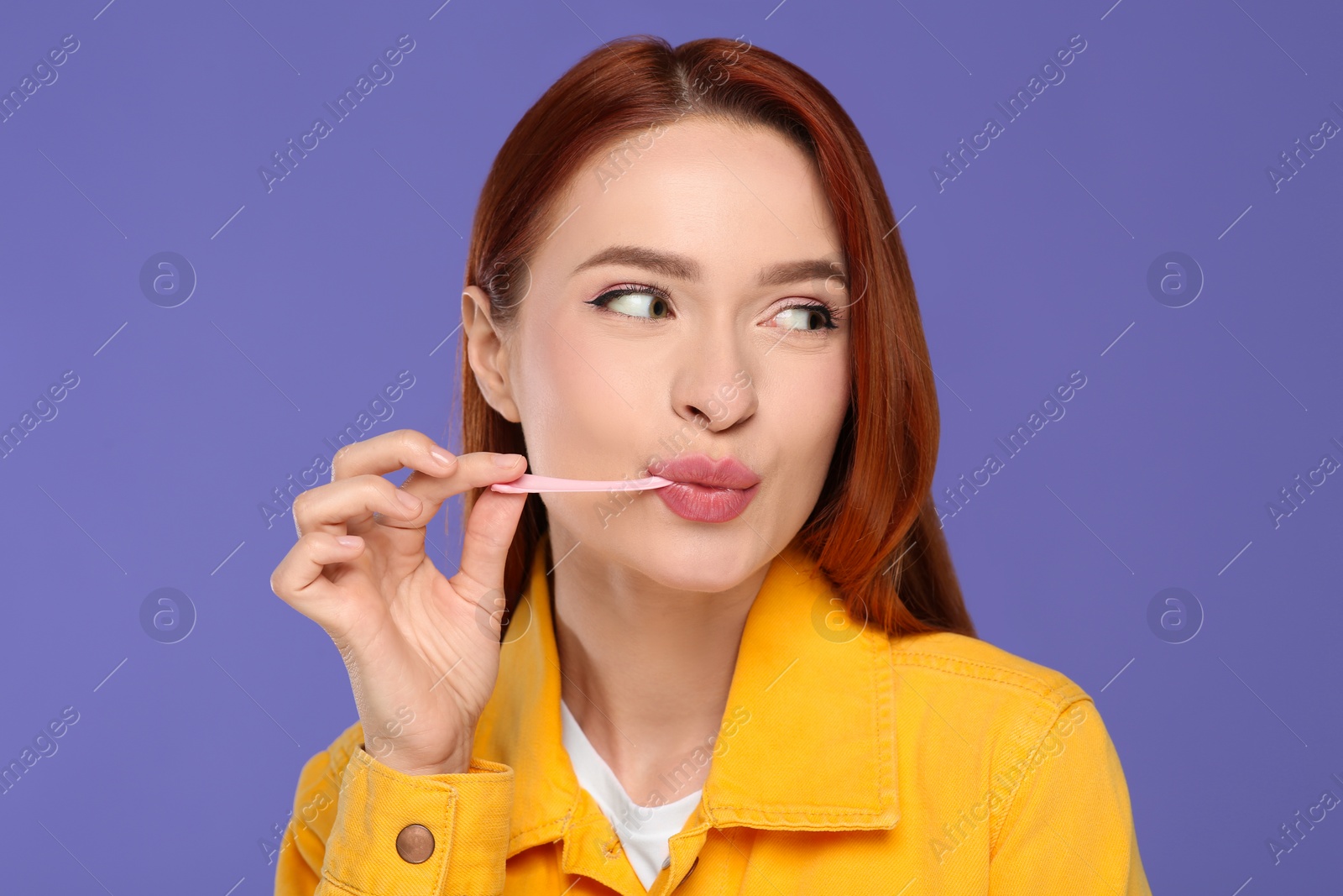 Photo of Beautiful woman chewing bubble gum on purple background