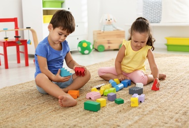 Photo of Cute little children playing with colorful blocks on floor indoors. Educational toy