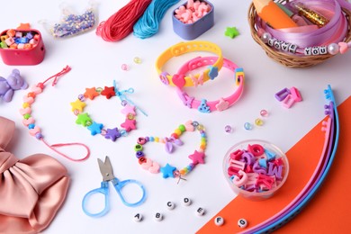 Kid's handmade beaded jewelry and different supplies on color background