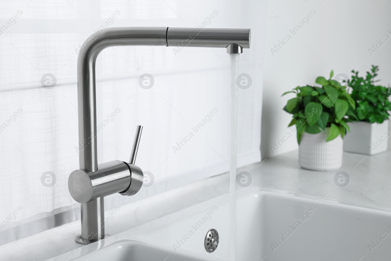 Photo of Stream of water flowing from tap in kitchen