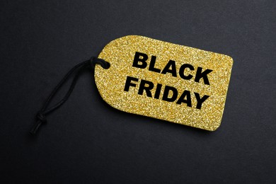 Golden tag with words Black Friday on dark background, top view