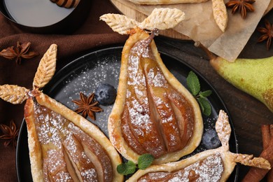 Photo of Delicious pears baked in puff pastry with powdered sugar served on table, top view