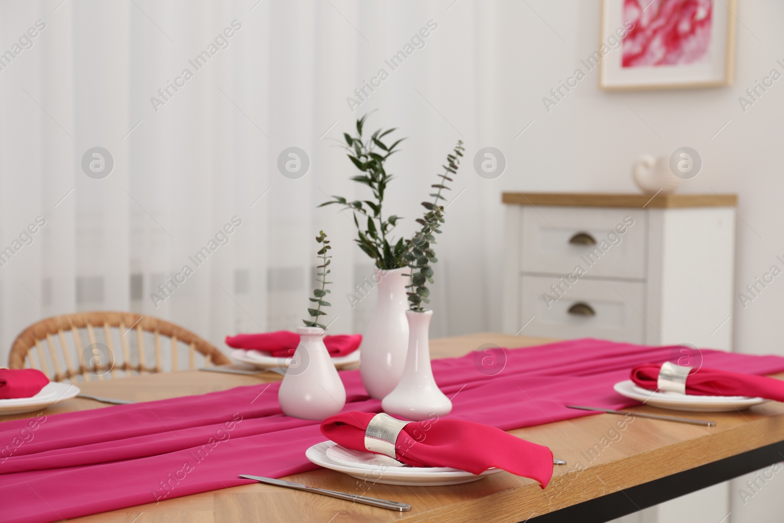 Photo of Beautiful table setting and vases with green branches in dining room