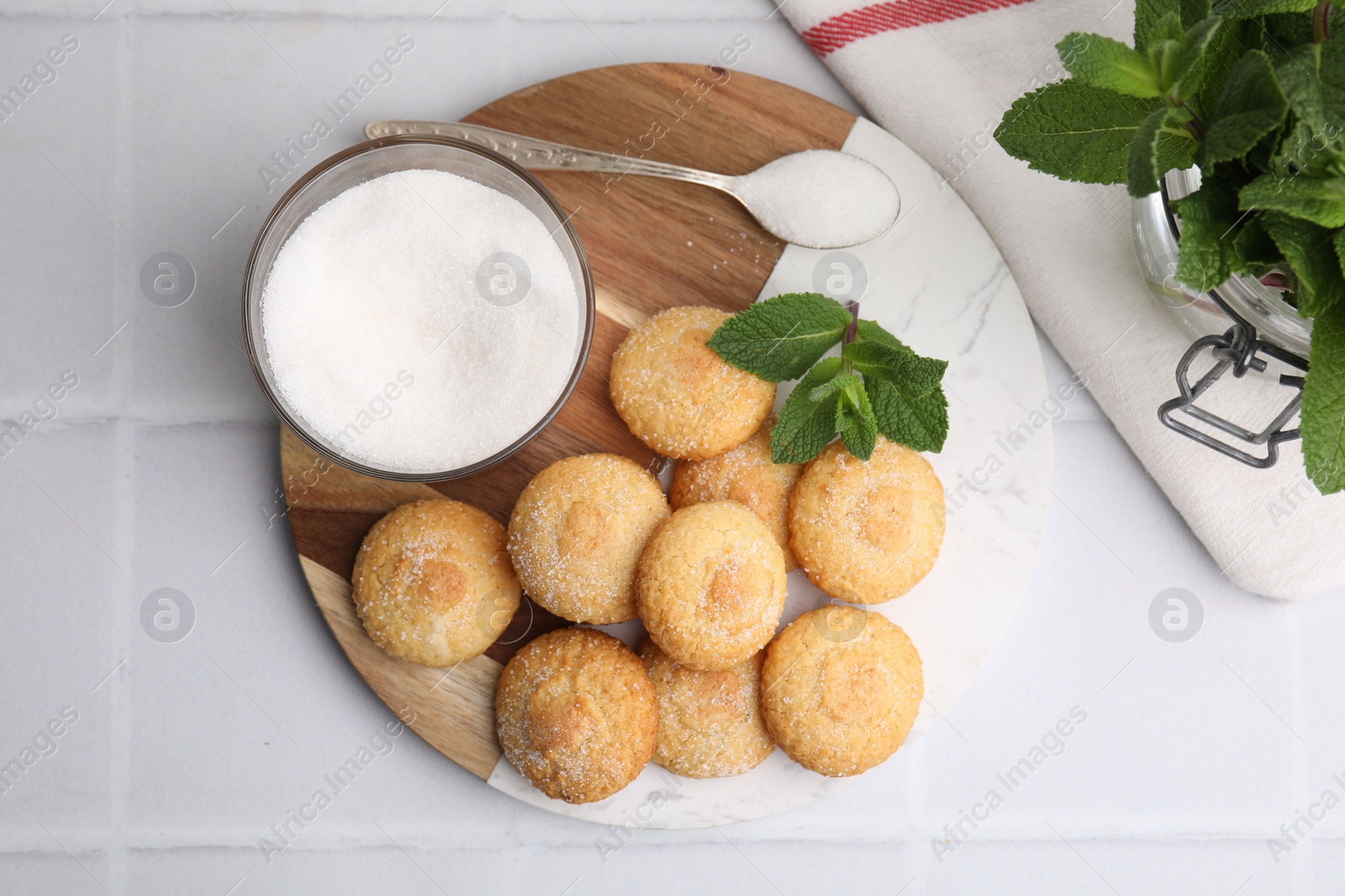 Photo of Tasty sweet sugar cookies and mint on white tiled table, top view