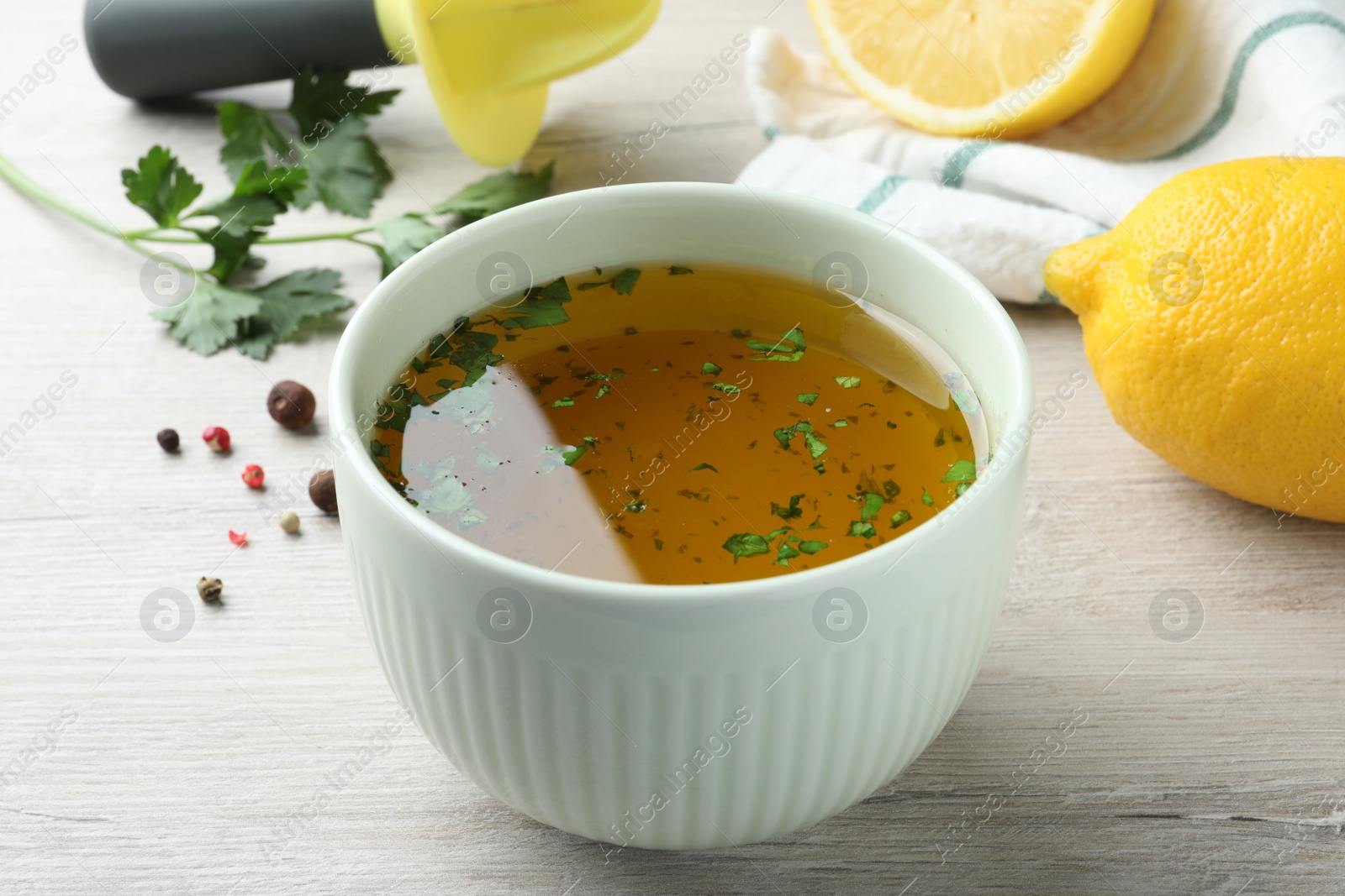 Photo of Bowl with lemon sauce on white wooden table. Delicious salad dressing