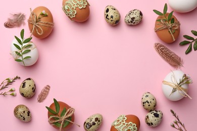 Photo of Frame made of festively decorated eggs and natural decor on pink background, top view with space for text. Happy Easter