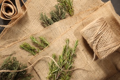 Photo of Natural burlap fabric, jute and fresh herbs on table, top view
