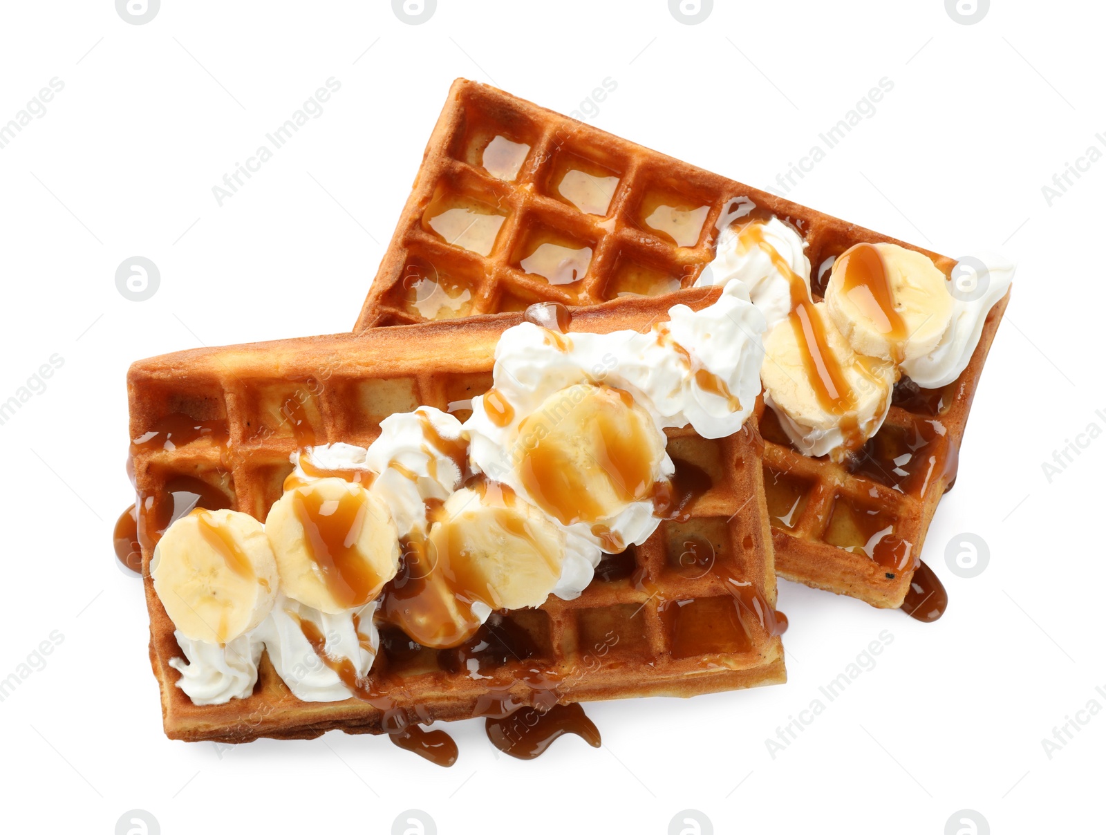Photo of Delicious Belgian waffles with banana, whipped cream and caramel sauce isolated on white, top view