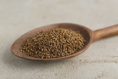 Photo of Spoon of celery seeds on light grey table, closeup