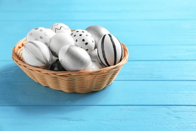 Photo of Wicker bowl of Easter eggs on table. Space for text