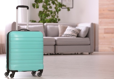 Photo of Colorful suitcase packed for journey in living room. Space for text