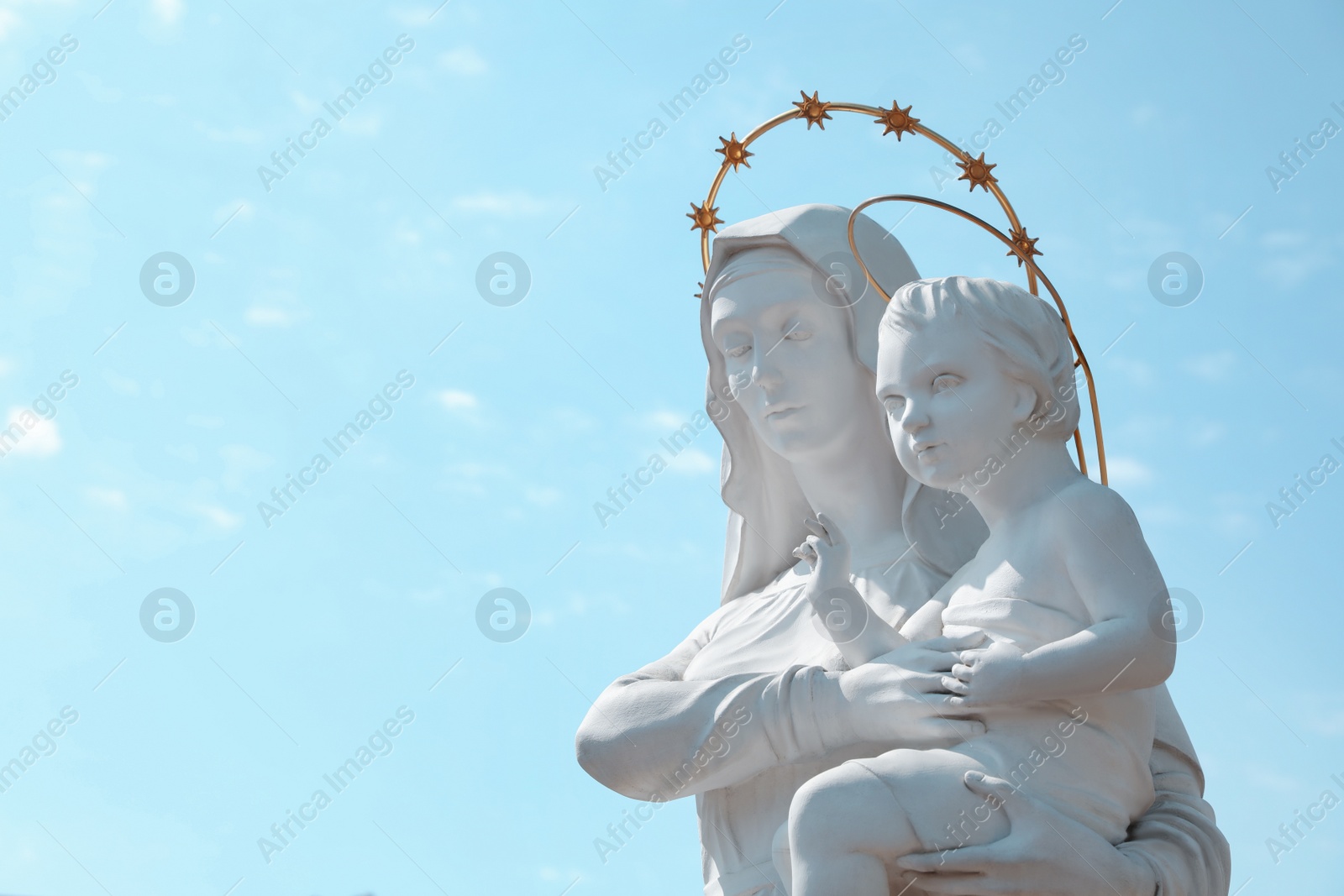 Photo of Beautiful statue of Virgin Mary and baby Jesus against blue sky. Space for text