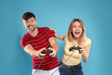 Photo of Emotional couple playing video games with controllers on color background