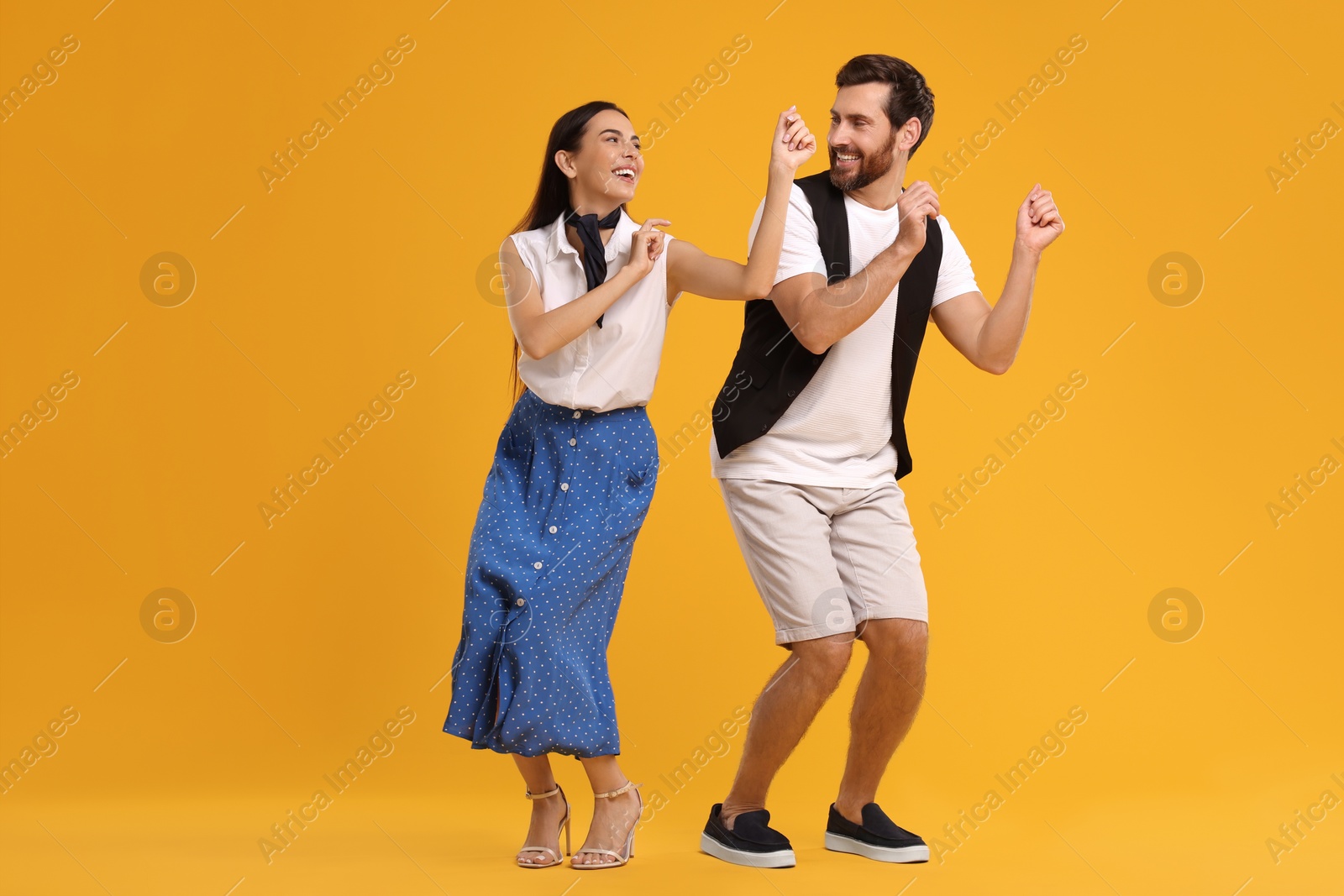 Photo of Happy couple dancing together on orange background