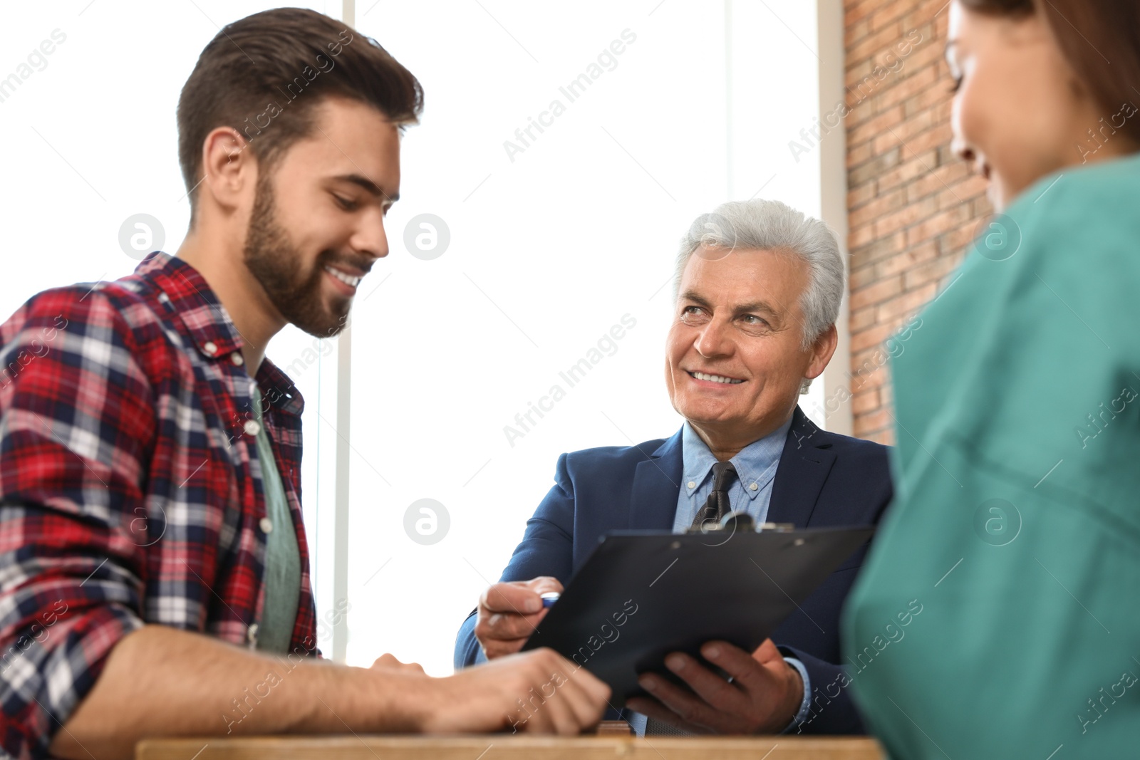 Photo of Senior notary working with young couple in office