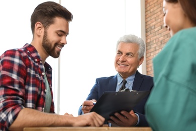 Senior notary working with young couple in office