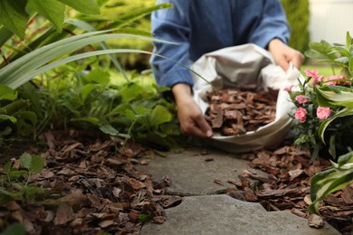 Photo of Woman holding sack with bark chips in garden, selective focus