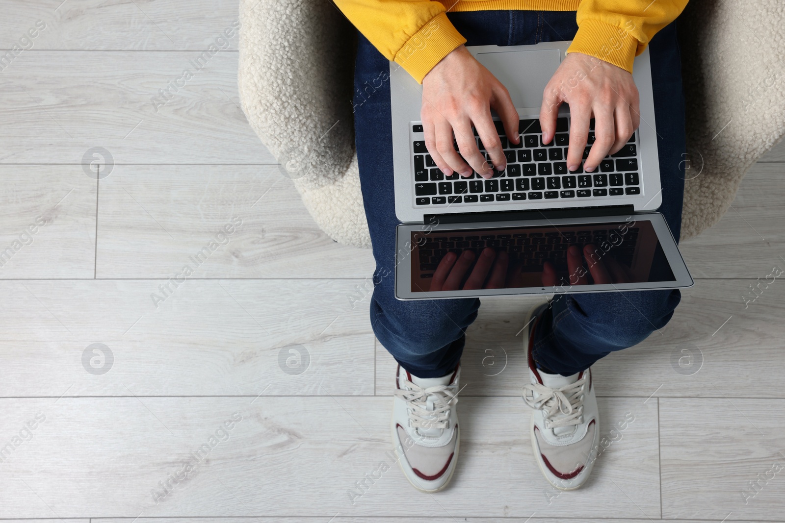 Photo of Man working with laptop in armchair, top view. Space for text